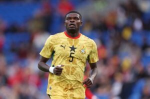 Soccer player in a yellow Ghana kit with number 5 on the field, looking focused in action.
