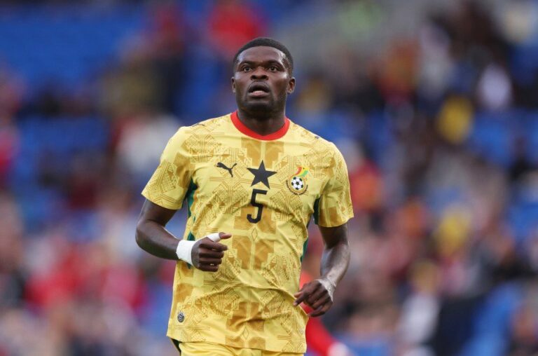 Soccer player in a yellow Ghana kit with number 5 on the field, looking focused in action.