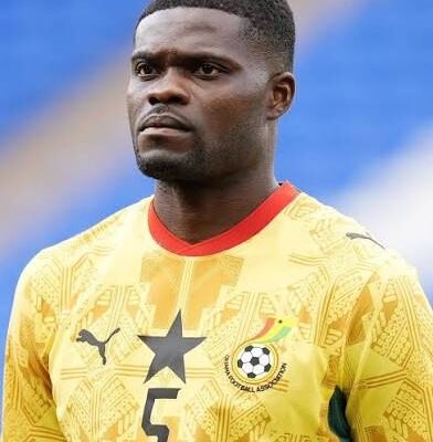 IMG_0917 | Ghanaguardian.com Male soccer player in a yellow jersey with a black star and the number 5, standing on a field with a blue background.