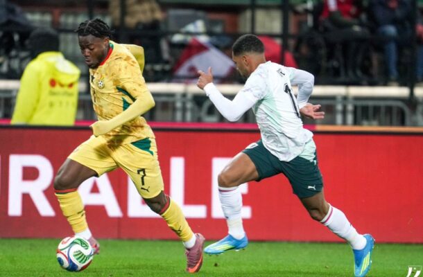 IMG_0919 | Ghanaguardian.com Two soccer players sprint for the ball during a match, the yellow-clad player wearing number 7 in the lead while the opponent in white and teal pursues closely.