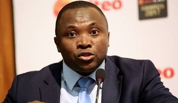 IMG_0948 | Ghanaguardian.com Man in a navy suit and light blue tie speaks at a microphone during a press conference or formal event.