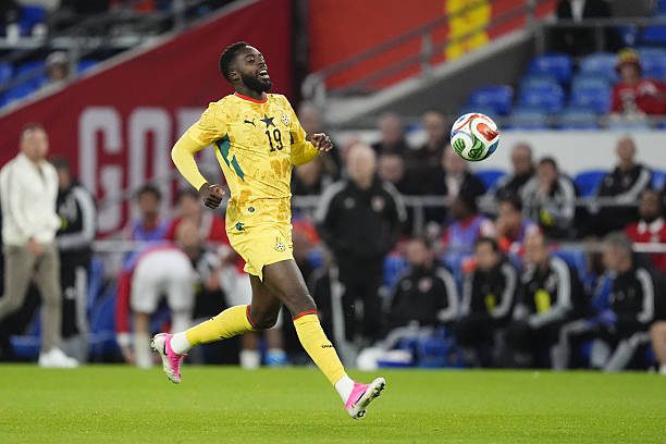 Soccer player in yellow kit with number 19 runs toward a ball on the field during a match.