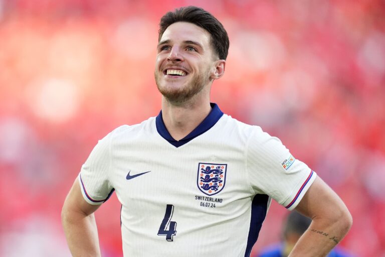 England national team footballer smiling on the pitch in a white away kit with crest and number 4 visible