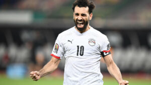 Soccer player in a white jersey with the number 10 celebrating with clenched fists.