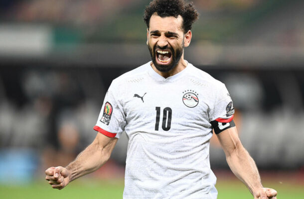 Soccer player in a white jersey with the number 10 celebrating with clenched fists.