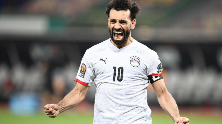 Soccer player in a white jersey with the number 10 celebrating with clenched fists.