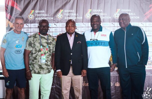 Five men stand in front of a Ghana Football Association backdrop posing for a photo at an event.