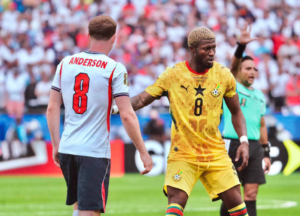 Two soccer players face off on the field; one in light blue with 'ANDERSON 8' and the other in yellow with a black star, during a match.