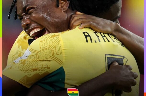 Two Ghanaian football players embrace in celebration, with the word 'QUALIFIED' and 'ROUND OF 32' on a graphic that includes the FIFA World Cup 2026 logo.