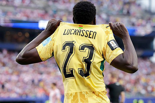 Soccer player seen from behind in a yellow jersey with name Luckassen and number 23, celebrating on the field.