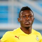 Male soccer player in a yellow jersey on a blurred stadium background, focused on the action.