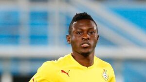 Male soccer player in a yellow jersey on a blurred stadium background, focused on the action.