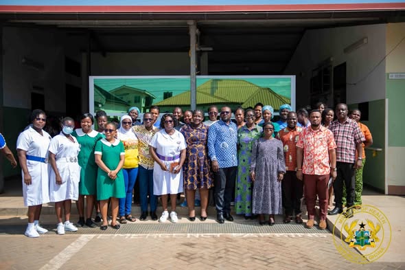 MO-1 | Ghanaguardian.com Group of about 30 adults in colorful clothing posing for a group photo outside a building, with a circular seal visible in the bottom right corner.