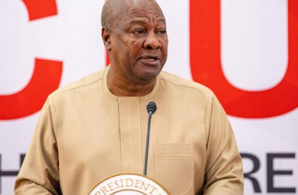 Mahama-TVET-696x571 | Ghanaguardian.com African man in a beige traditional shirt speaking at a podium with a microphone in front of a bold red-and-white backdrop and presidential seal