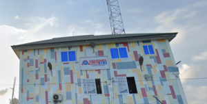 Colorful mural-covered two-story building housing Obatanpa Radio 92.5, with a tall antenna on the roof rail and blue windows.