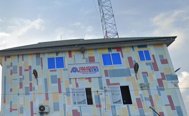 Colorful mural-covered two-story building housing Obatanpa Radio 92.5, with a tall antenna on the roof rail and blue windows.