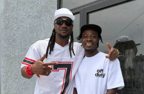 Two men posing outside a building; left man wears a white cap, sunglasses, and a white jersey with a large number 7, right man wears a white T‑shirt that says 'off duty'.