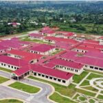 Aerial view of a campus with red-roofed buildings, green lawns, and circular garden paths.