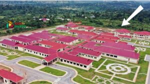 Aerial view of a campus with red-roofed buildings, green lawns, and circular garden paths.