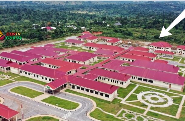 Aerial view of a campus with red-roofed buildings, green lawns, and circular garden paths.