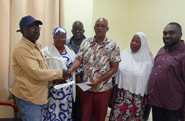 WhatsApp Image 2026-06-11 at 075805 | Ghanaguardian.com Six people stand in a room as two men shake hands and exchange envelopes, others watching nearby.