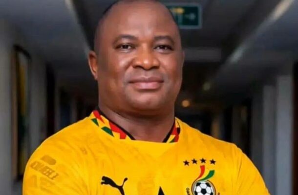 aaa | Ghanaguardian.com Portrait of a smiling man in a yellow football jersey standing in a dim hallway.