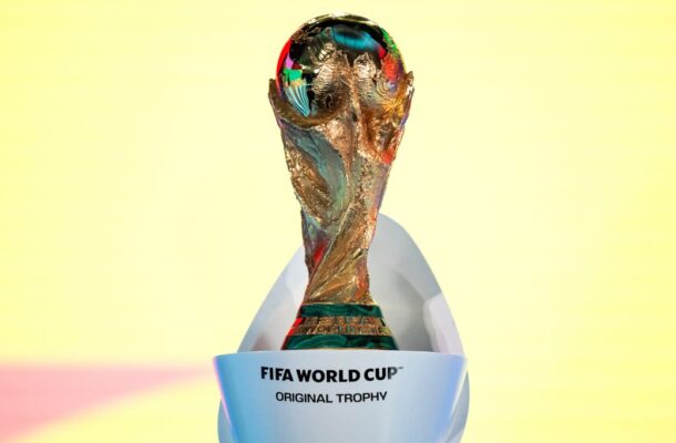 FIFA World Cup Original Trophy displayed on a white stand against a pale yellow background, front view core details visible
