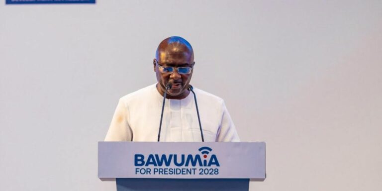 Man in white traditional attire speaks at a podium labeled 'BAWUMIA FOR PRESIDENT 2028'