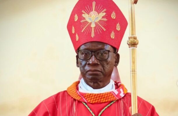 Catholic bishop wearing a red mitre and robe, holding a ceremonial staff during a liturgical ceremony.