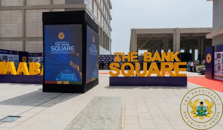 Promotional display reading THE BANK SQUARE with large orange letters at an outdoor event; blue info panels nearby and the presidential seal in the bottom-right corner.