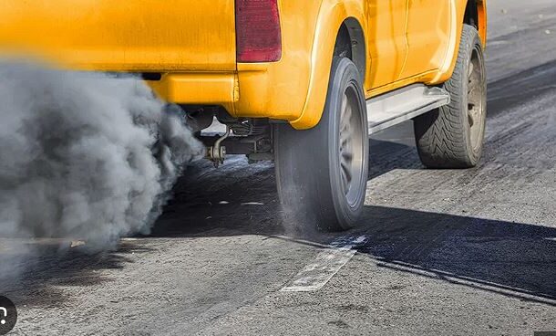 emmisson | Ghanaguardian.com Rear of a yellow taxi emitting dark exhaust smoke as it drives on a road.