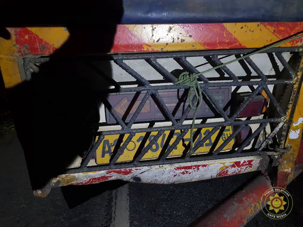 Close-up of a metal barrier with a green rope tied around its bars; a yellow license plate is visible behind the bars during low light.
