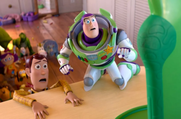 image-213-754x424 | Ghanaguardian.com Buzz Lightyear and Woody lean over a table edge with surprised expressions as a tall green toy stands nearby; a cluttered toy room is in the background.