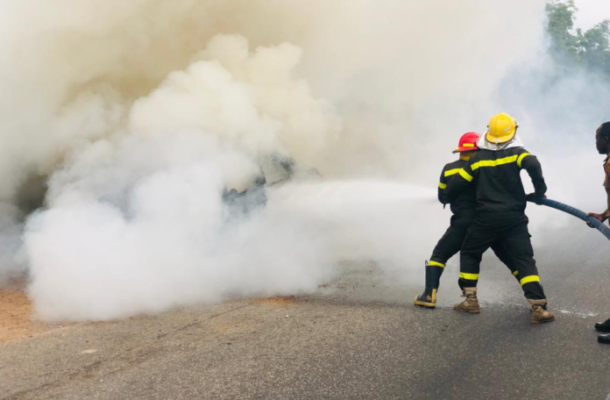 image-59-696x522 | Ghanaguardian.com Firefighters in protective gear spraying water to control a blaze on a smoky road scene.