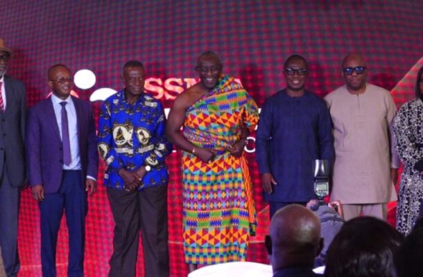 image_870x_6a1fecd520fd3 | Ghanaguardian.com Seven people pose on a stage with a red patterned backdrop during a formal event.