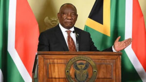 President delivering a speech at a wooden podium with the presidential seal; national flags behind him.