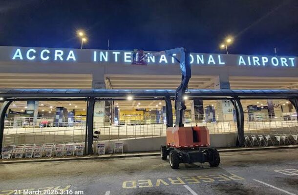 Night view of Accra International Airport with a mobile elevating work platform in the foreground near the terminal entrance.