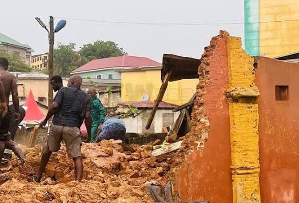 images-2 | Ghanaguardian.com Group of men standing amid rubble and a partially collapsed brick wall in an urban street, with damaged buildings in the background.