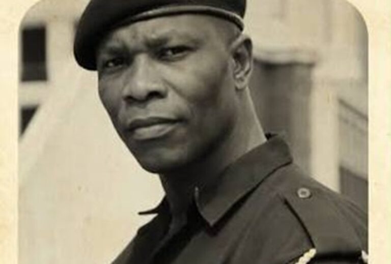 Black-and-white portrait of a man in a military-style uniform wearing a beret, looking at the camera.