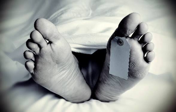 Feet of a deceased person with a toe tag under a blanket, indicating identification.