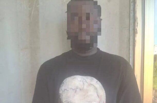tema | Ghanaguardian.com Man standing indoors against a concrete wall, wearing a black T-shirt with a large white skull graphic.