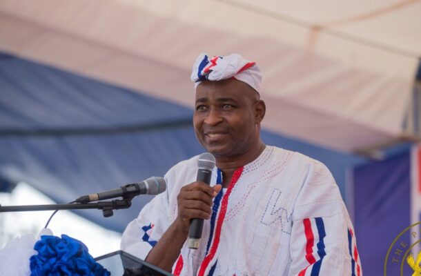 wontumi | Ghanaguardian.com Man in white traditional outfit with a head wrap speaks into a microphone at an outdoor event under a tent.