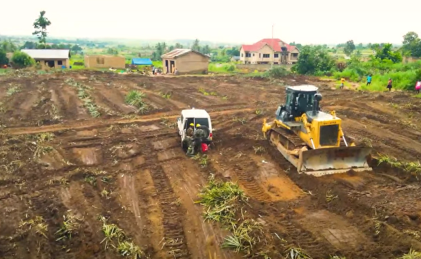 01072026_111212_REC-750x375 | Ghanaguardian.com Bulldozer and a yellow excavator work on a cleared dirt lot in a rural area with houses in the background, preparing land for construction.