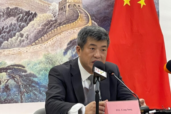 25674205 | Ghanaguardian.com Asian man in a dark suit seated at a table during a press conference, speaking into microphones, with a Chinese flag and Great Wall mural behind him.