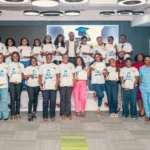 Group of graduates and organizers on stage, holding certificates at a Female Engineers Academy graduation ceremony.