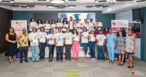 Group of graduates and organizers on stage, holding certificates at a Female Engineers Academy graduation ceremony.