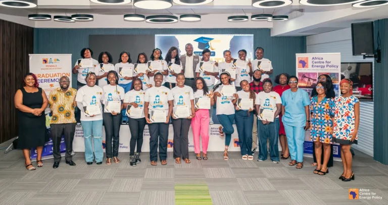 Group of graduates and organizers on stage, holding certificates at a Female Engineers Academy graduation ceremony.
