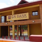Facade of a GN Bank branch with a yellow and brick exterior and a sign reading 'GN BANK The People's Bank' above the entrance; a few people near the doorway.