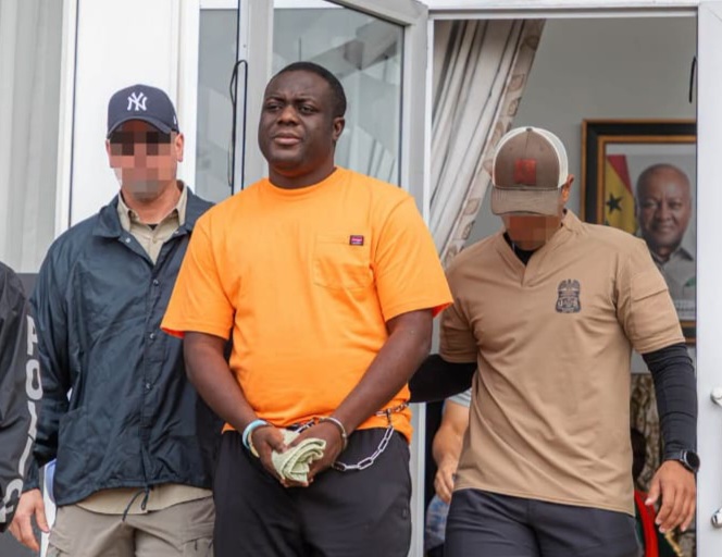 Man in an orange shirt is handcuffed in front, flanked by two men with pixelated faces near a doorway.
