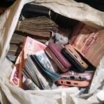 A white bag filled with stacks of cash and several old mobile phones piled inside.